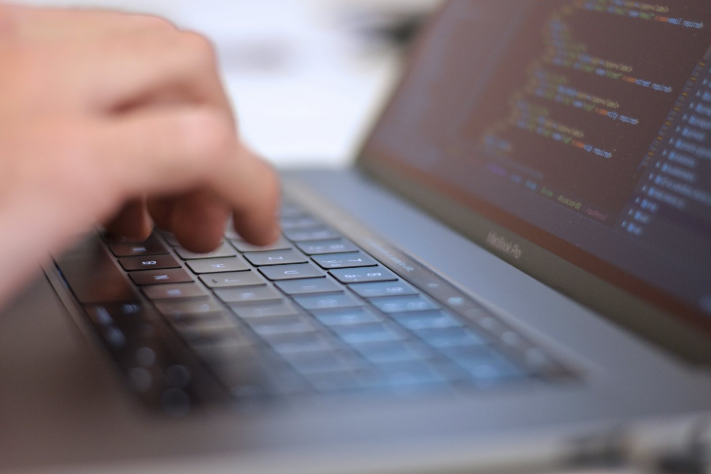 Mani che digitano righe di codice di programmazione su una tastiera di laptop.