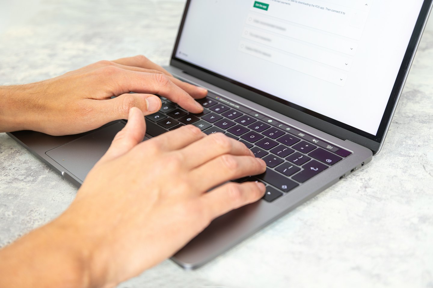 Mani che digitano su una tastiera di laptop con uno schermo luminoso.